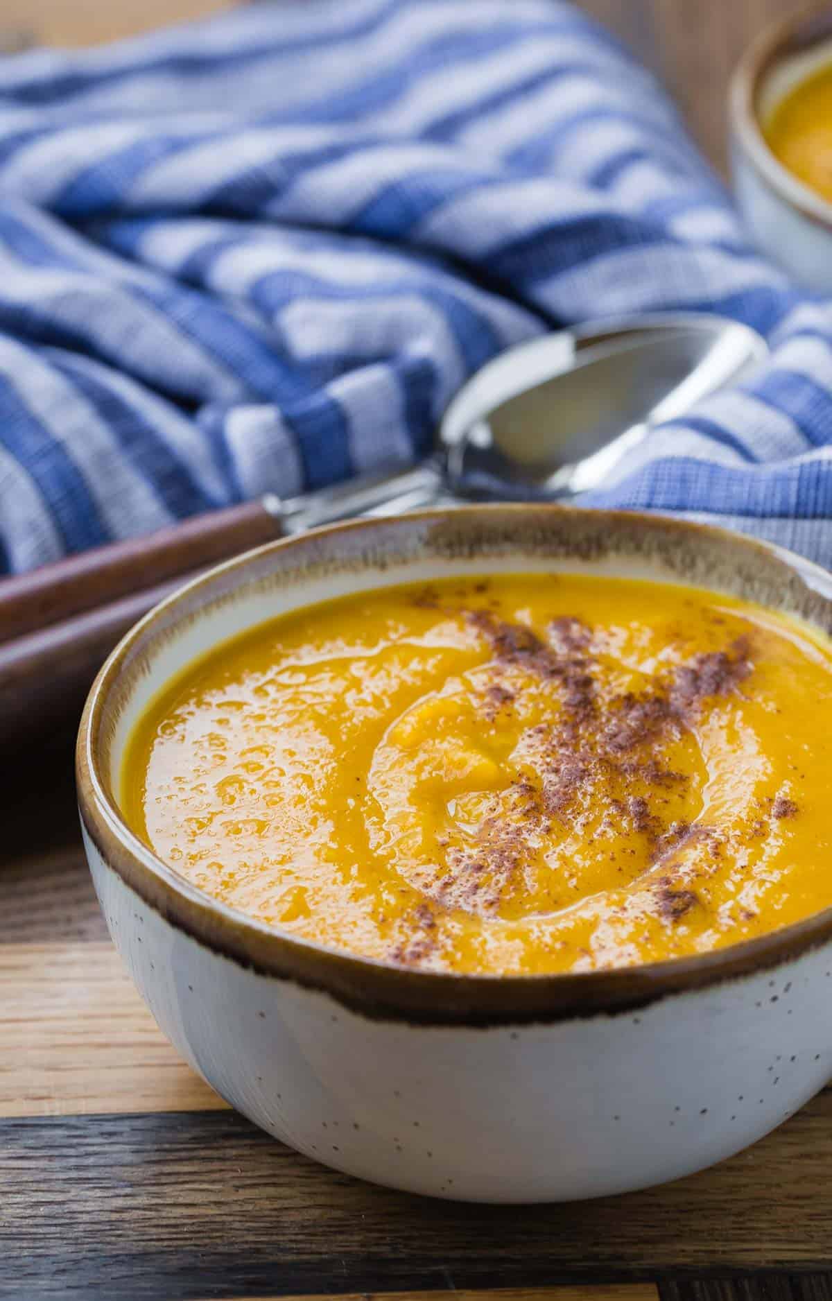 Bowl of homemade squash soup with a blue and white linen in the background.