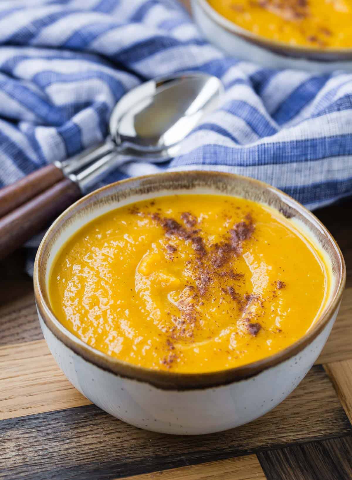 Bowl of squash soup, with spoons and a cloth napkin in the background.