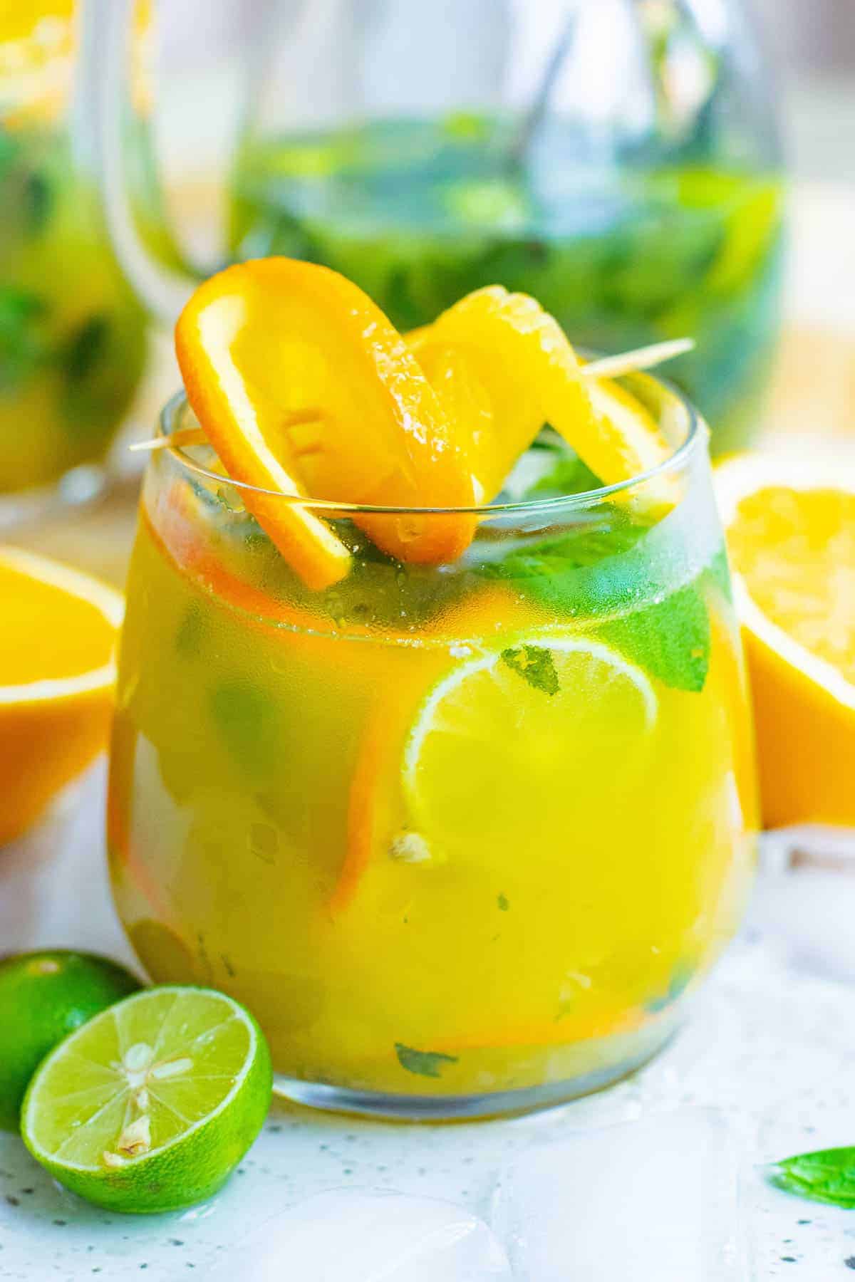 Orange mojito in a clear glass, garnished with mint and fresh orange.