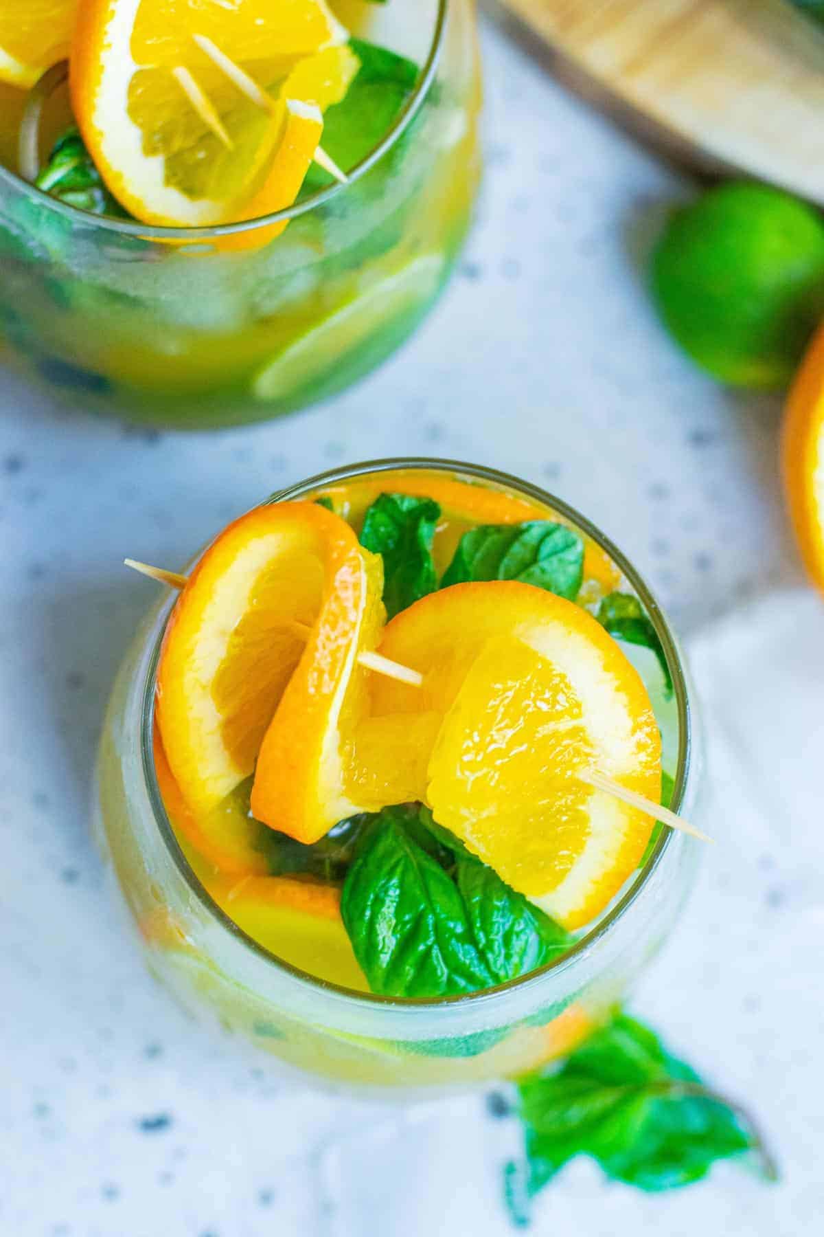 Overhead view of a cocktail garnished with orange and mint.