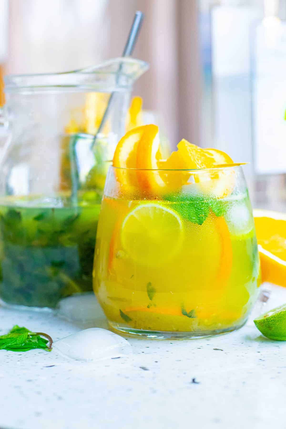 Mojito made with orange juice, pitcher in the background. 