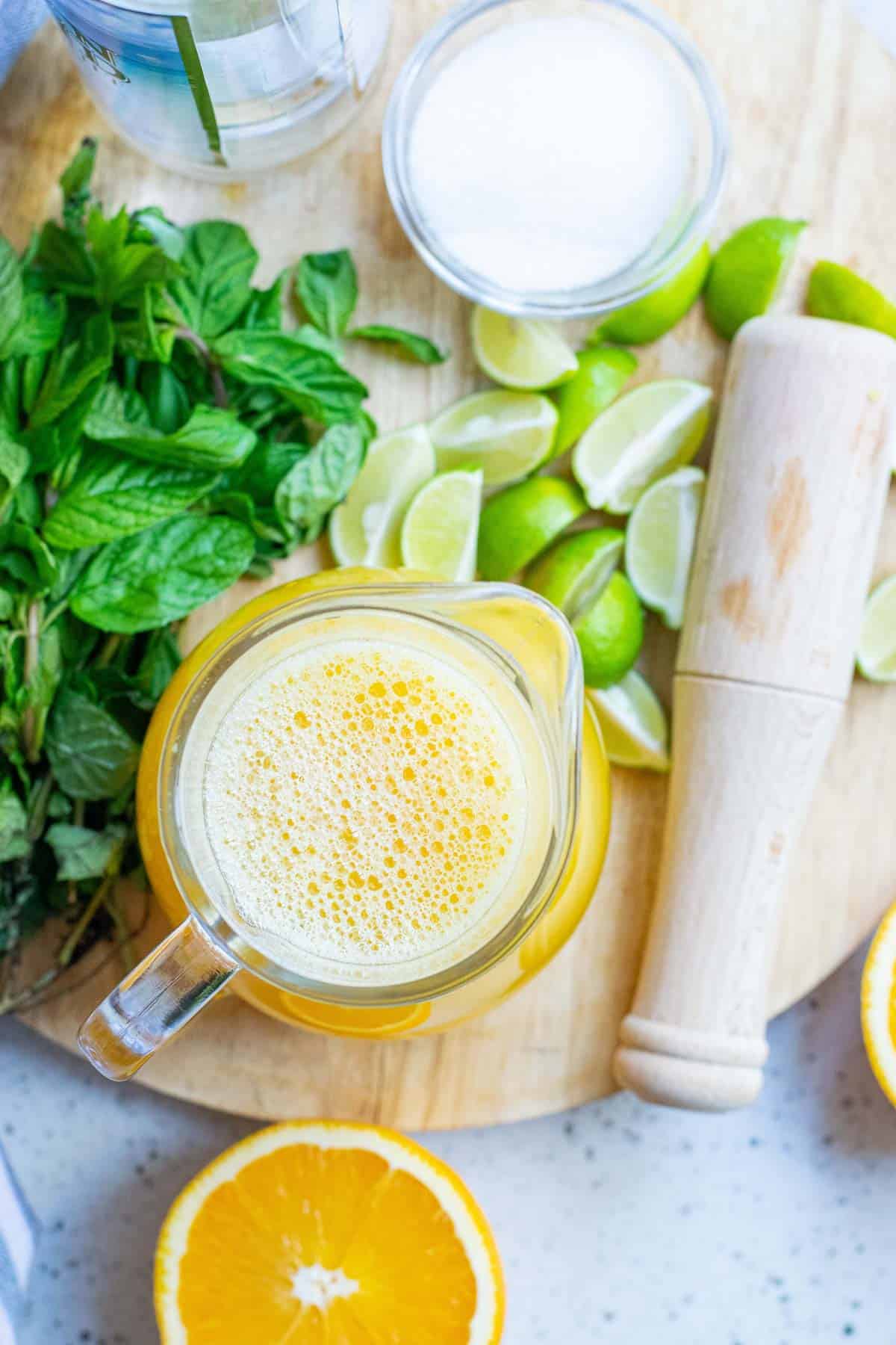 Fresh orange juice, lime wedges, granulated sugar, and fresh mint leaves.