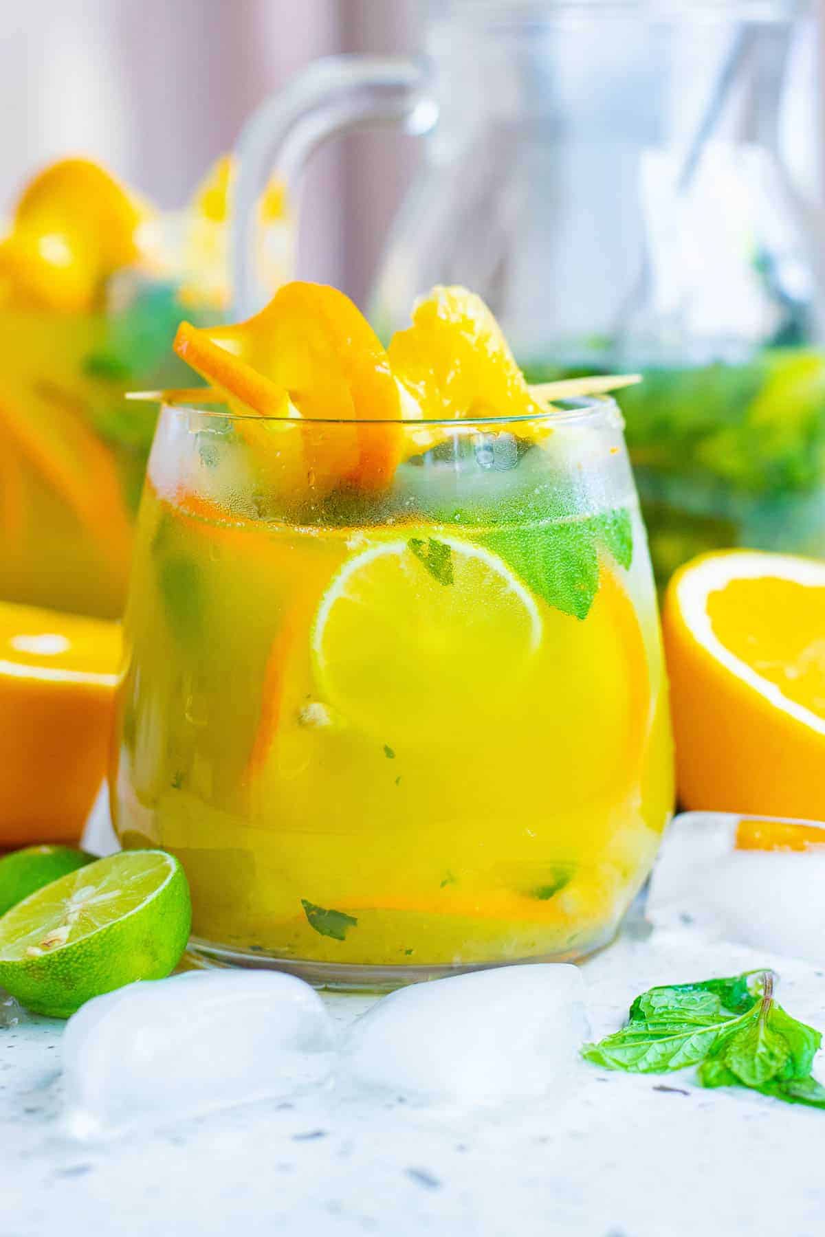 Straight-on view of an orange cocktail with mint leaves.