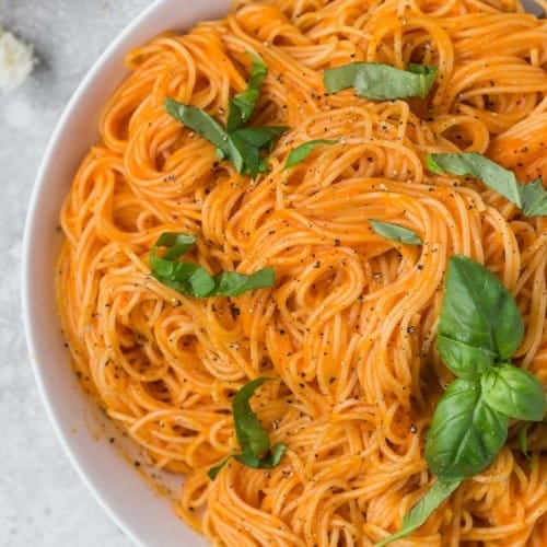 Large bowl of angel hair pasta with a simple roasted red pepper sauce.
