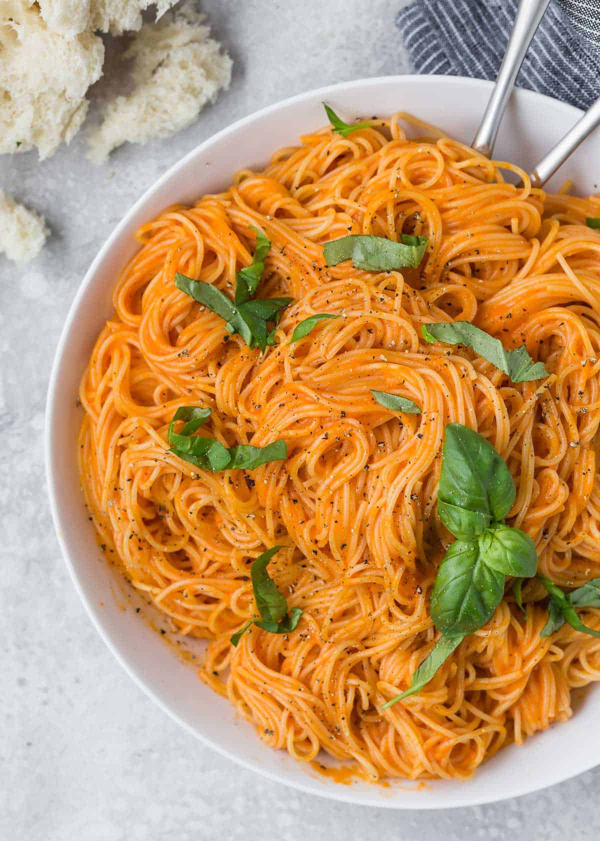 Overhead view of angel hair in a light orange sauce, garnished with fresh basil.