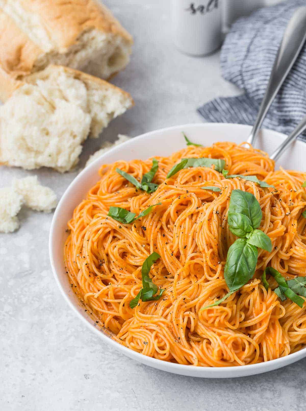 Large bowl of angel hair pasta with a light orange vegetarian pasta sauce made with roasted red peppers.