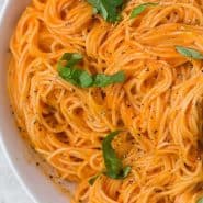 Overhead view of pasta in a bowl, text overlay reads "roasted red pepper sauce and angel hair"