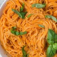 Overhead view of pasta in a bowl, text overlay reads "roasted red pepper sauce and angel hair"