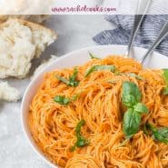 Pasta in a bowl with light red sauce and fresh basil, text overlay reads "roasted red pepper sauce and angel hair"