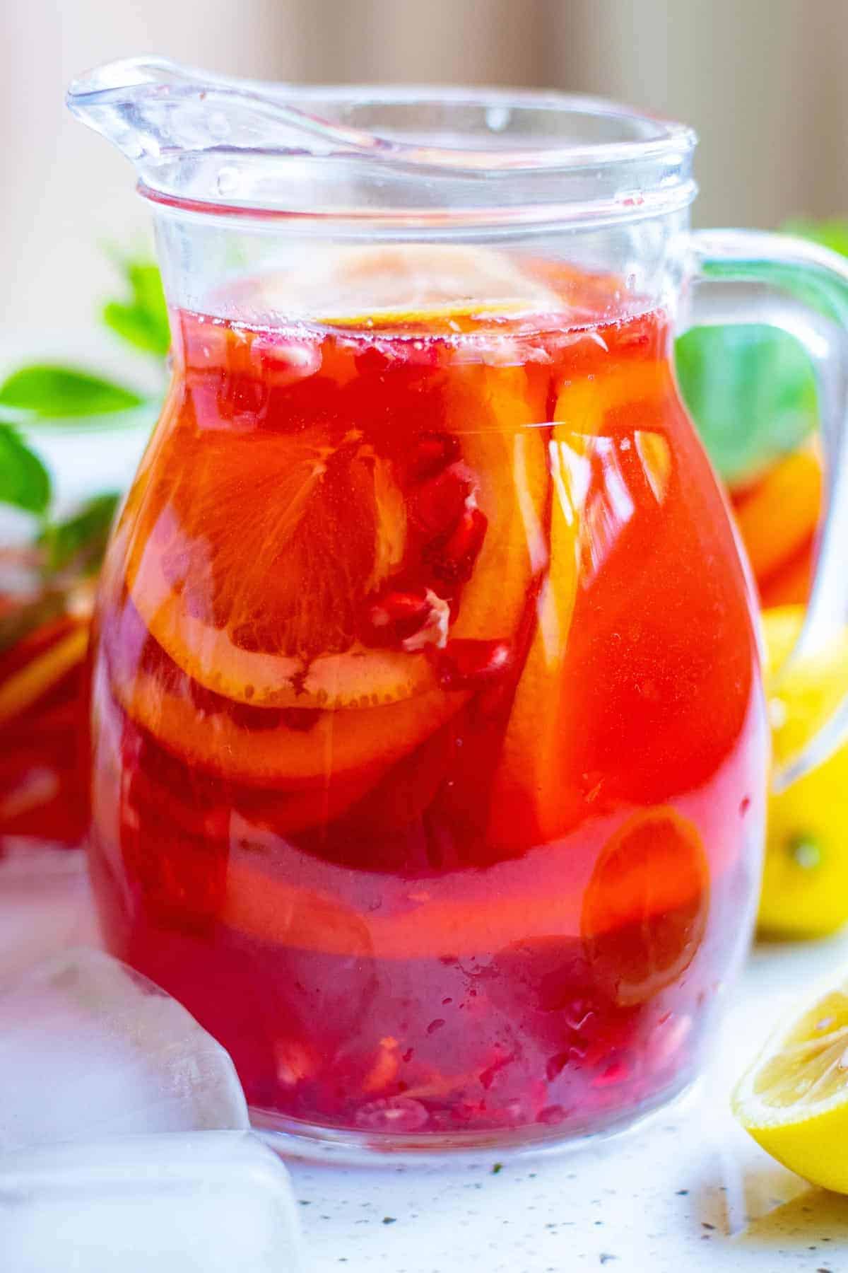 Pitcher of bright red punch with citrus slices.