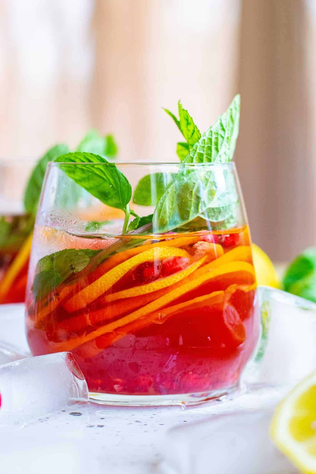 Bright red pomegranate punch garnished with citrus slices, fresh mint, and pomegranate arils.
