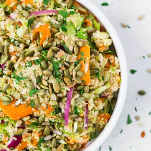 Overhead view of a white bowl filled with quinoa and colorful vegetables.