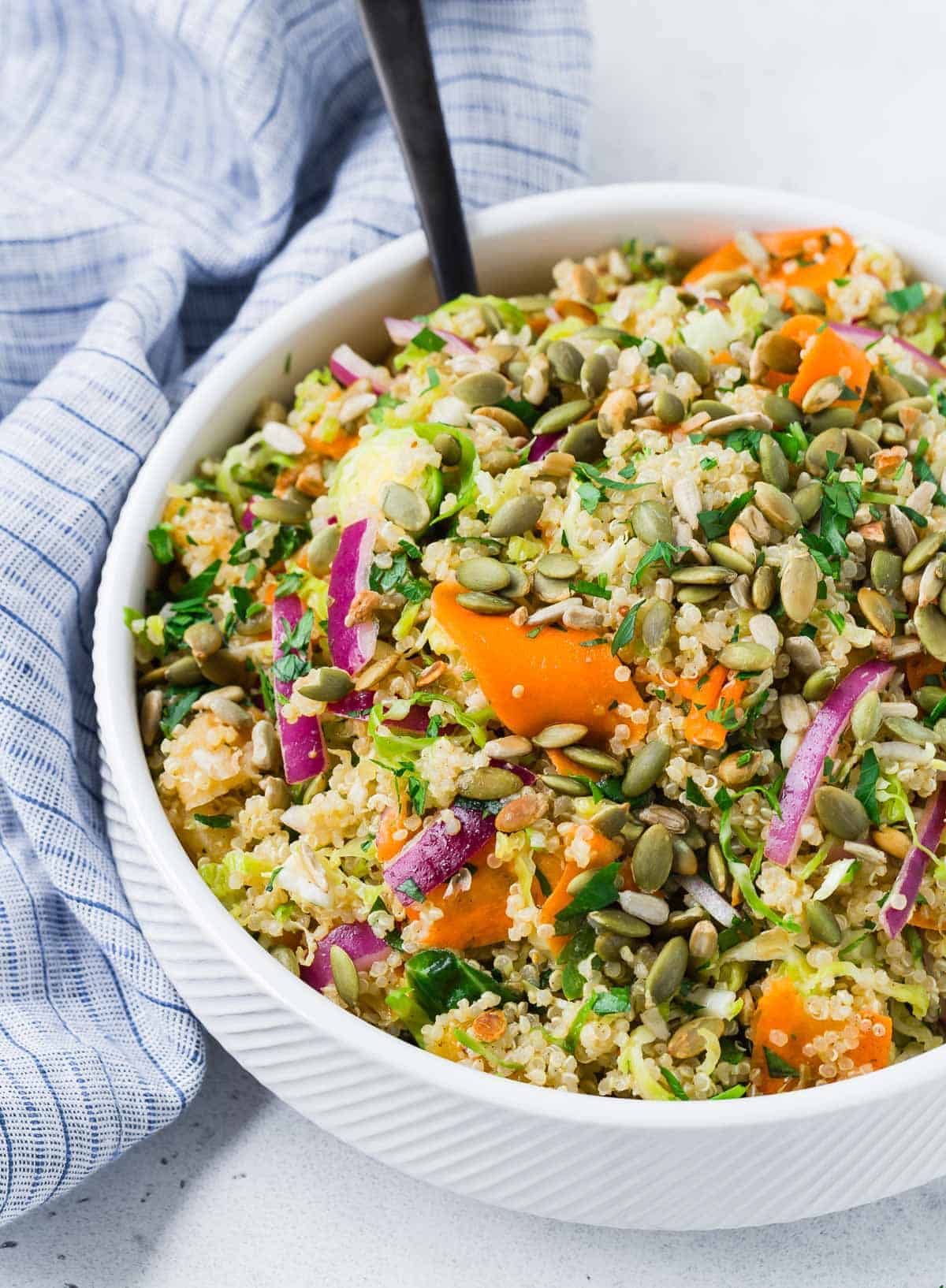 Quinoa salad in a white bowl on a light grey background.