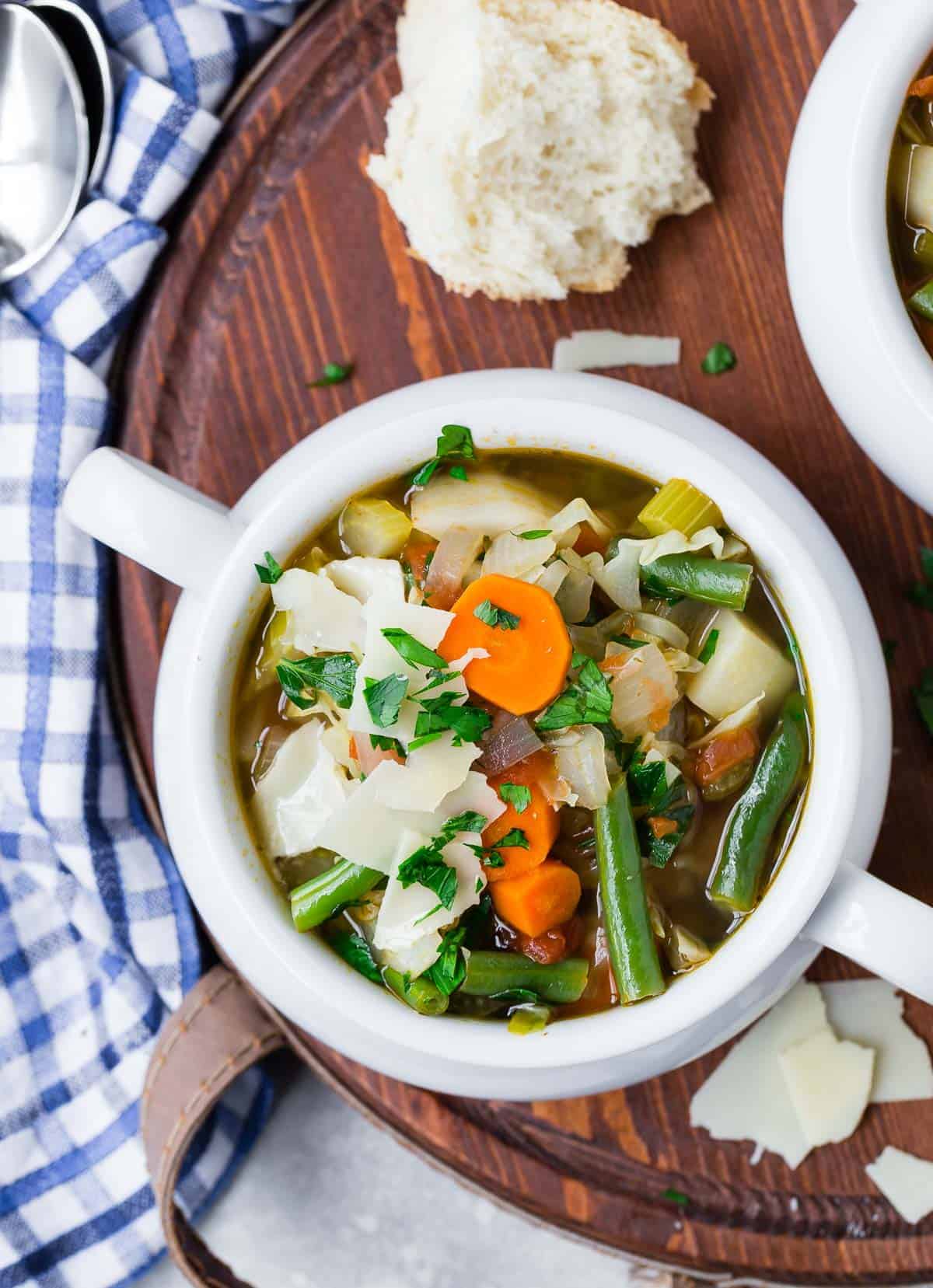 Overhead view of a bowl of soup with carrots, green beans, and more.