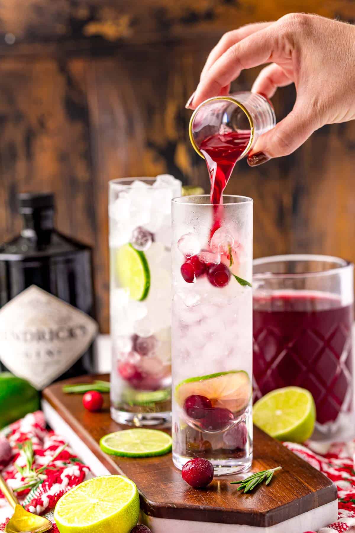 Cranberry being poured into a G&T cocktail.