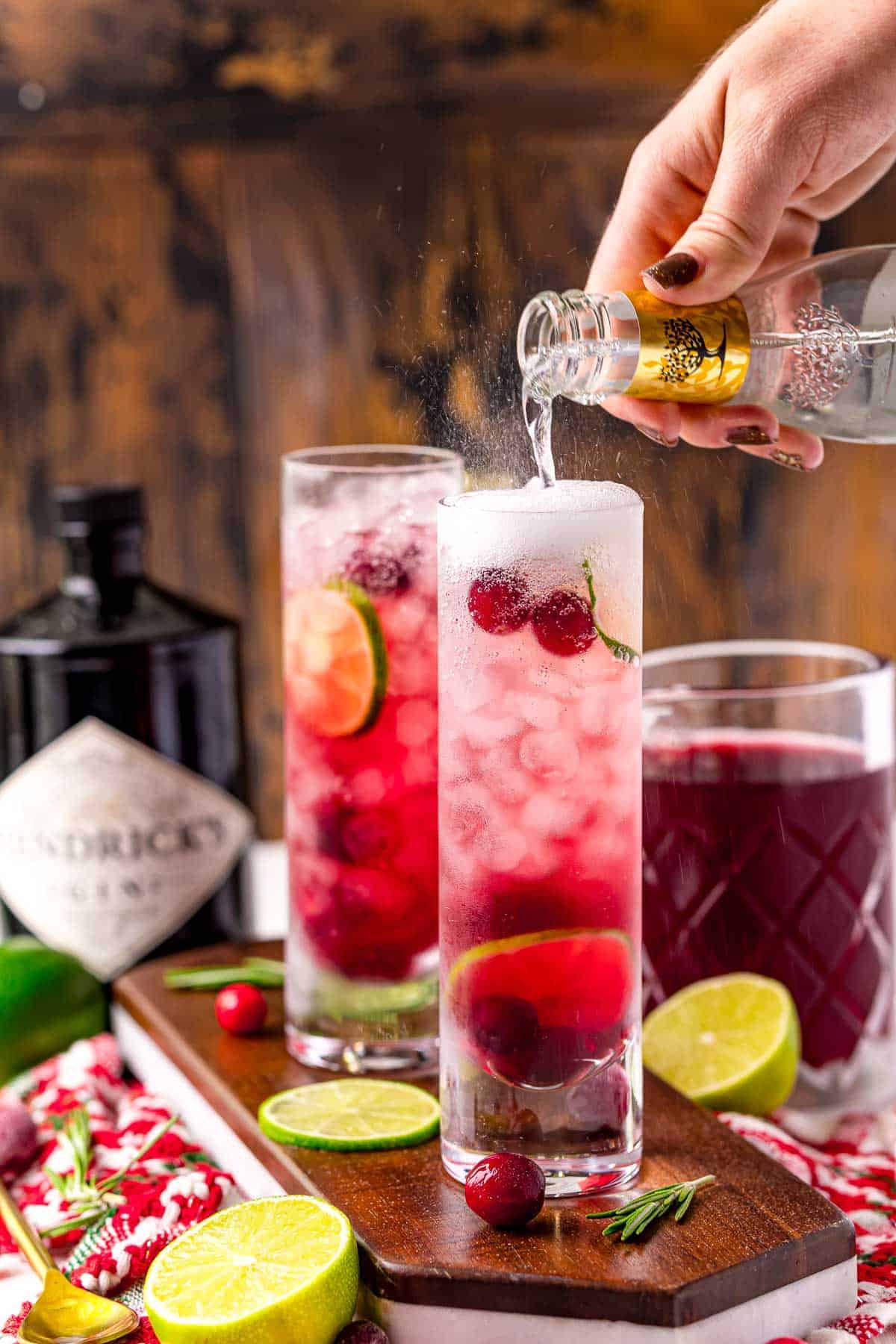 Tonic water being added to a red cocktail.