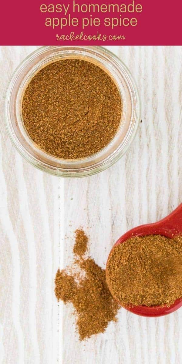 Apple pie spice mixture on a spoon, and in a jar on a white wooden background.