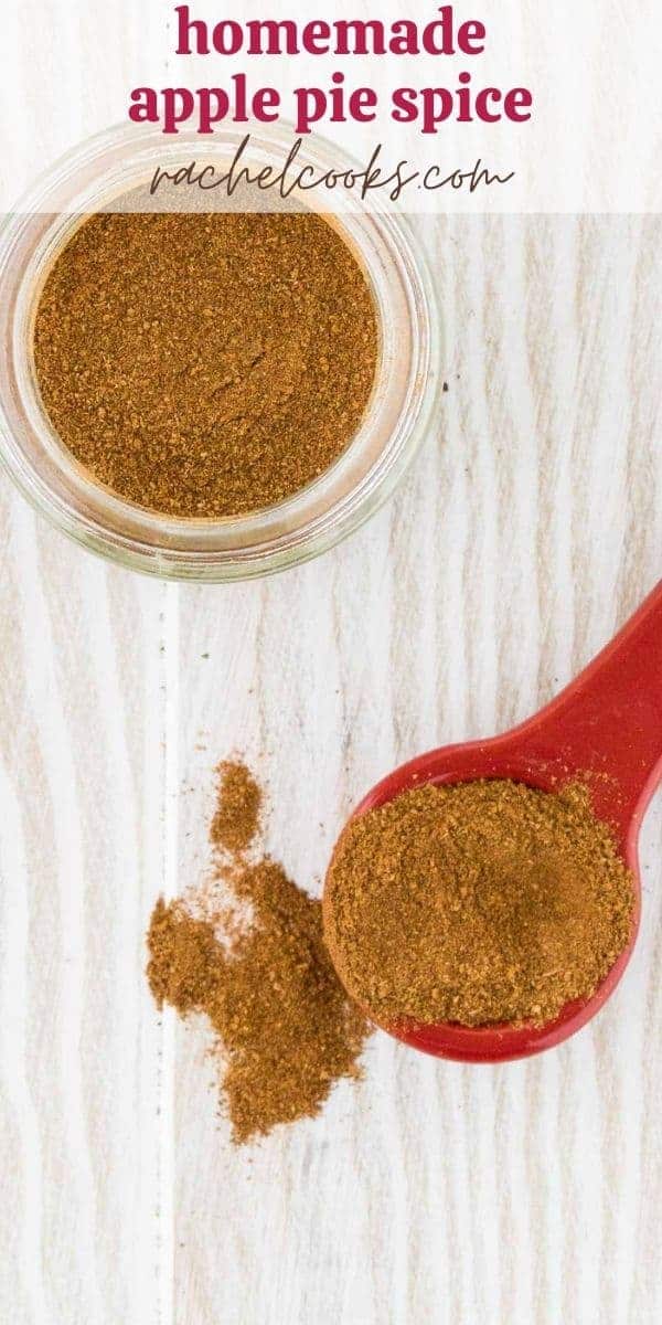 Apple pie spice mixture on a spoon, and in a jar on a white wooden background.