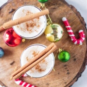 Overhead view of two festive cocktails garnished with cinnamon sticks.