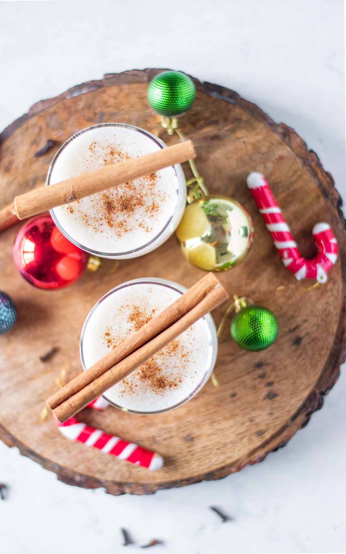 Overhead view of two festive cocktails garnished with cinnamon sticks.