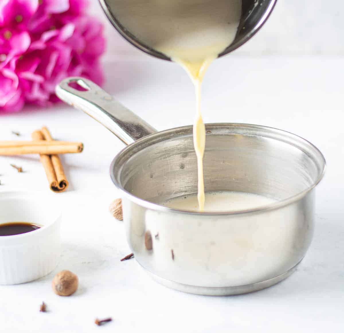 Uncooked eggnog being poured into a saucepan.