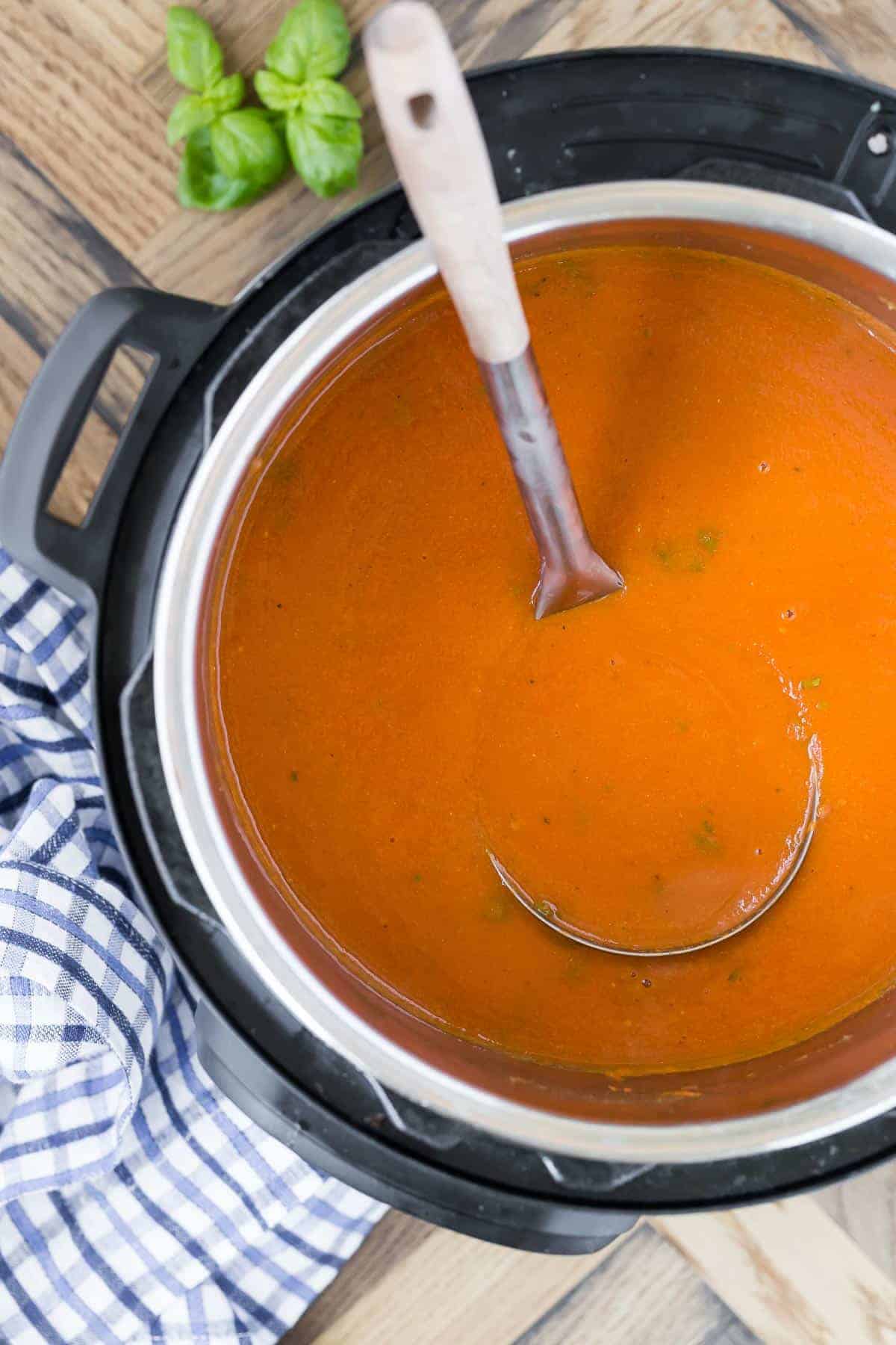 Tomato soup in an instant pot with a ladle.