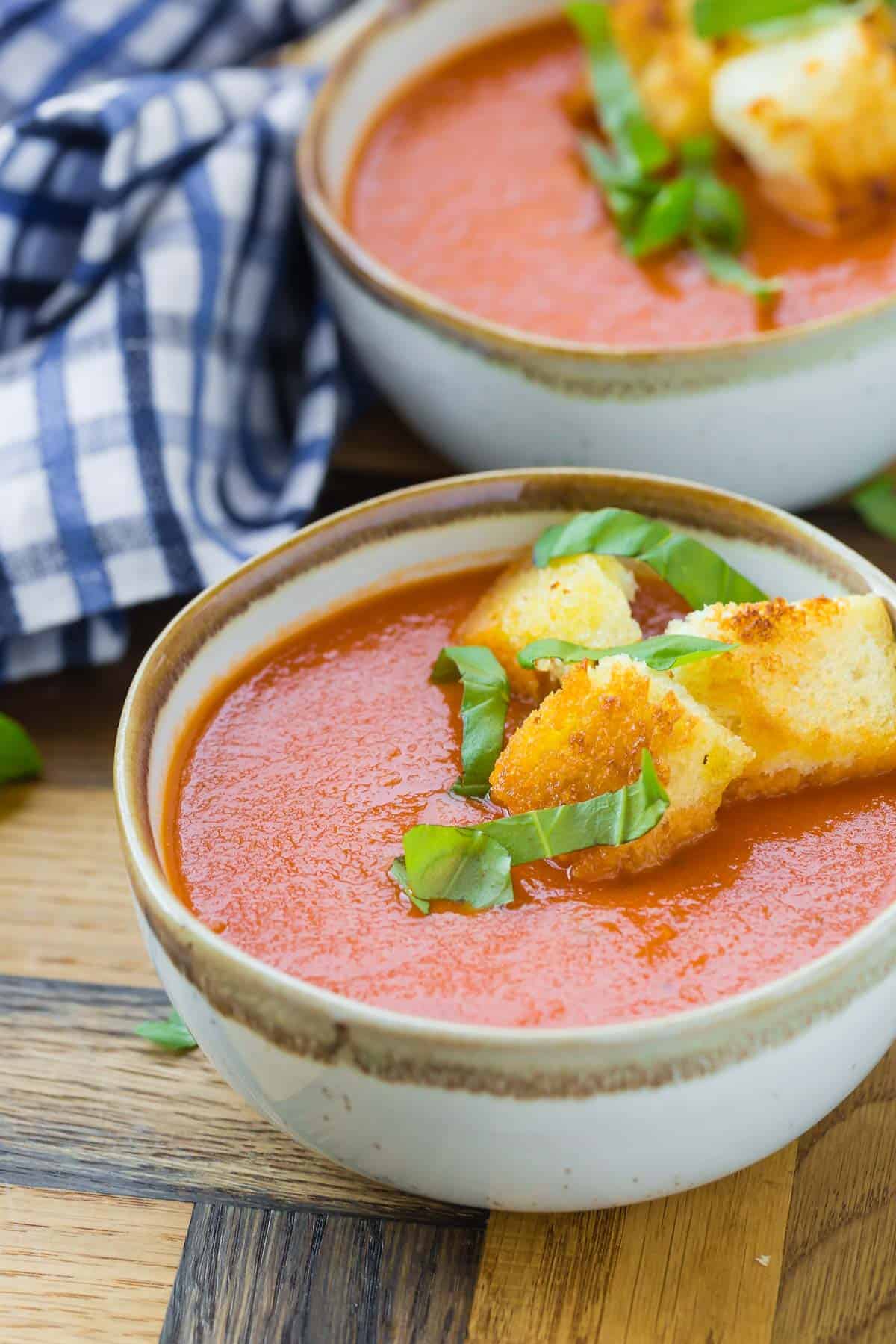 Close up of creamy tomato soup in a bowl, topped with homemade croutons.
