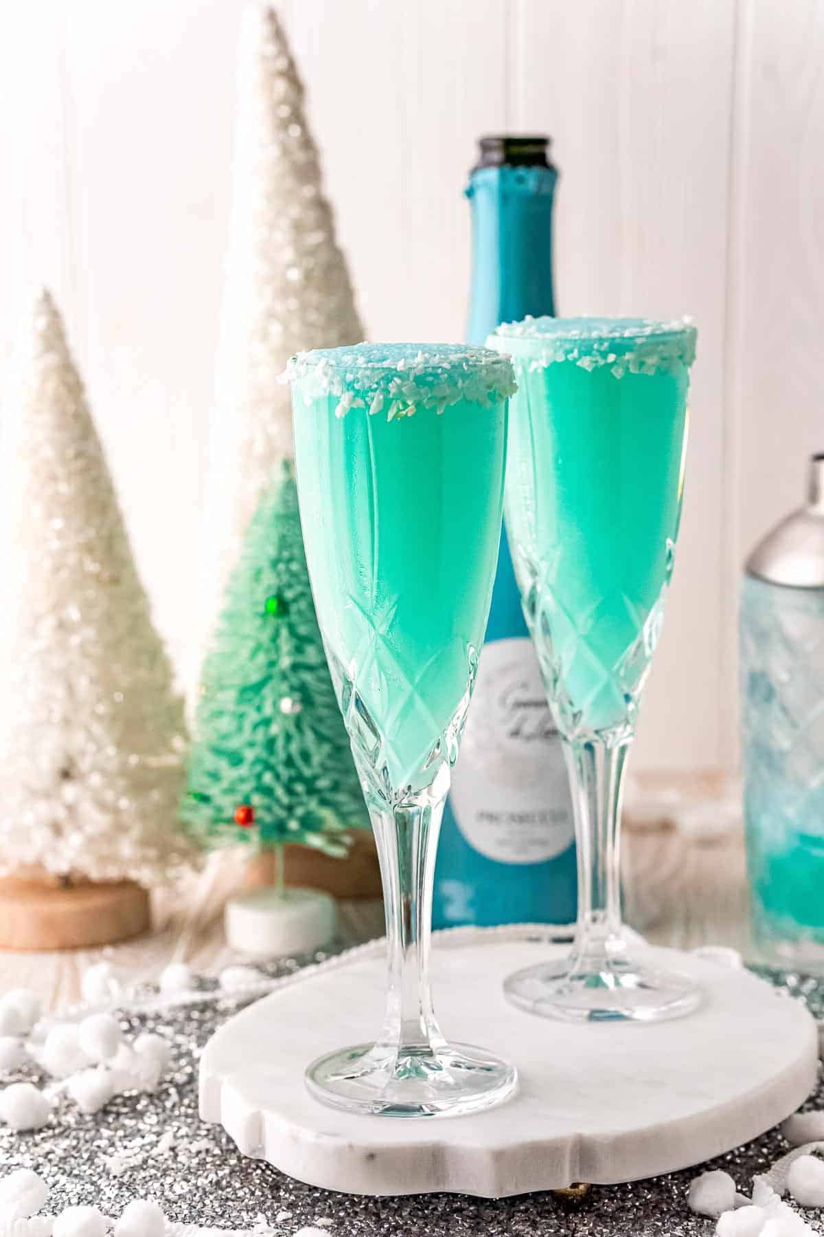 Two bright blue mimosas with a festive winter background.