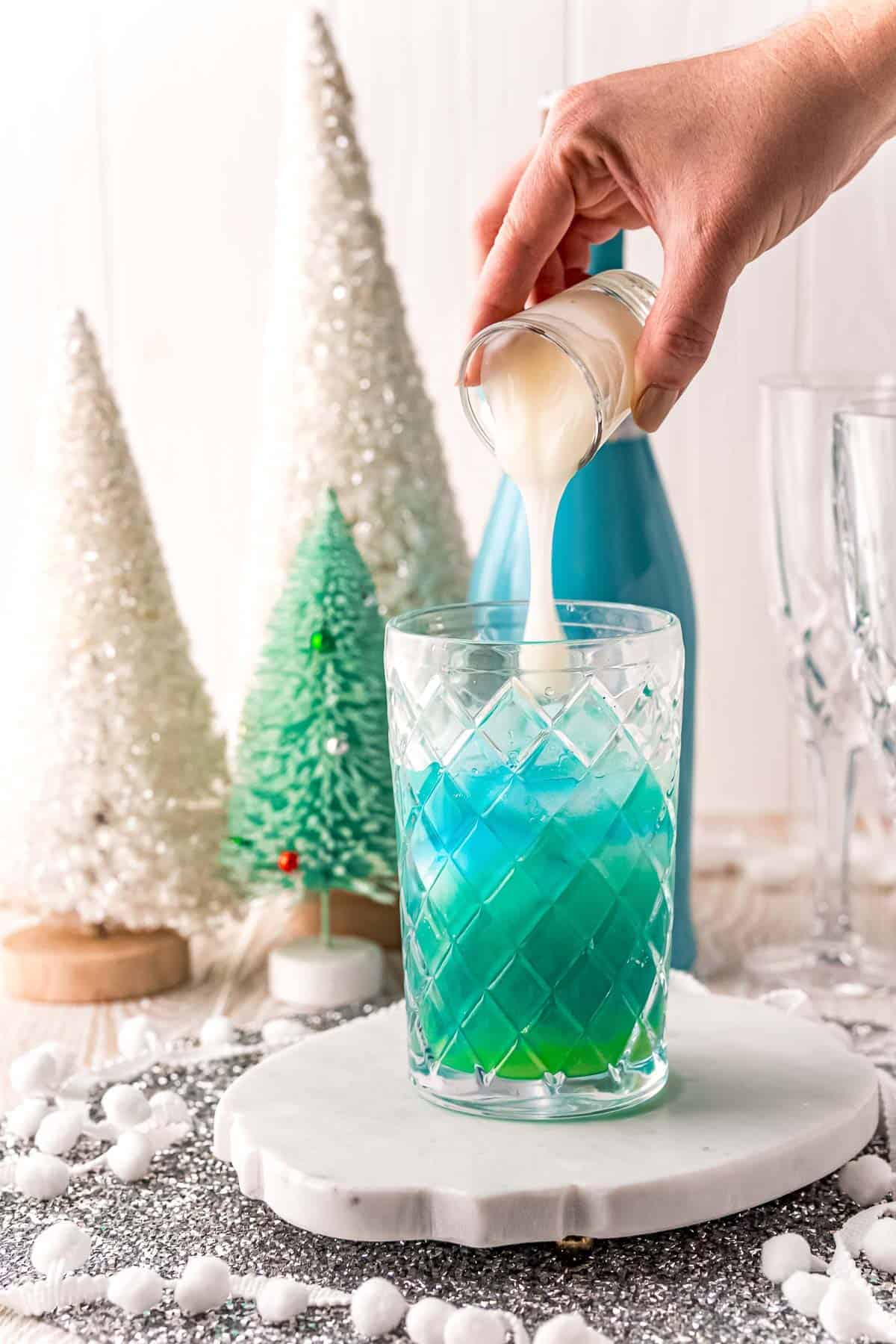 White liquid being poured into blue liquid.