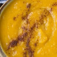 Bowl of orange colored soup, text overlay reads "healthy kabocha squash soup"
