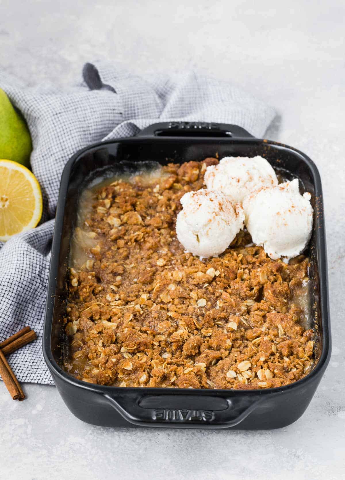 Baked pear dessert with crisp topping, garnished with ice cream.