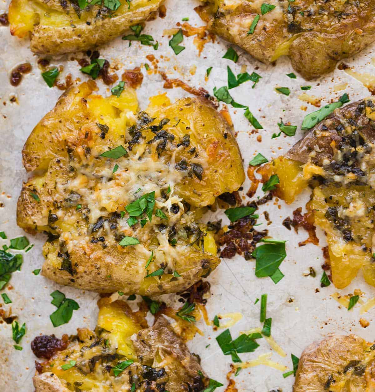 Close up overhead view of a smashed potato with garlic butter, parmesan, and parsley.