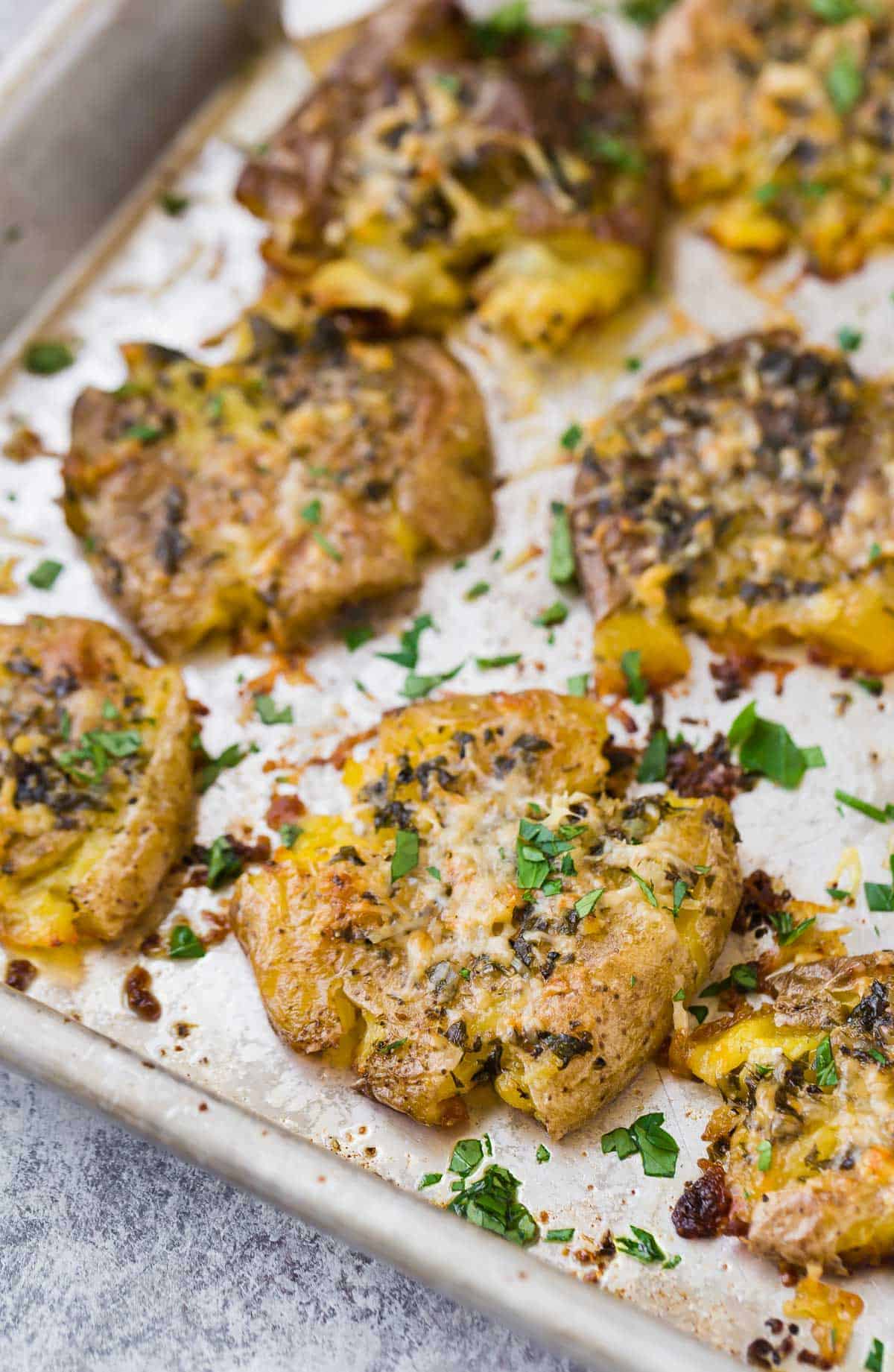 Close up of a crispy smashed potato on a sheet pan with others.