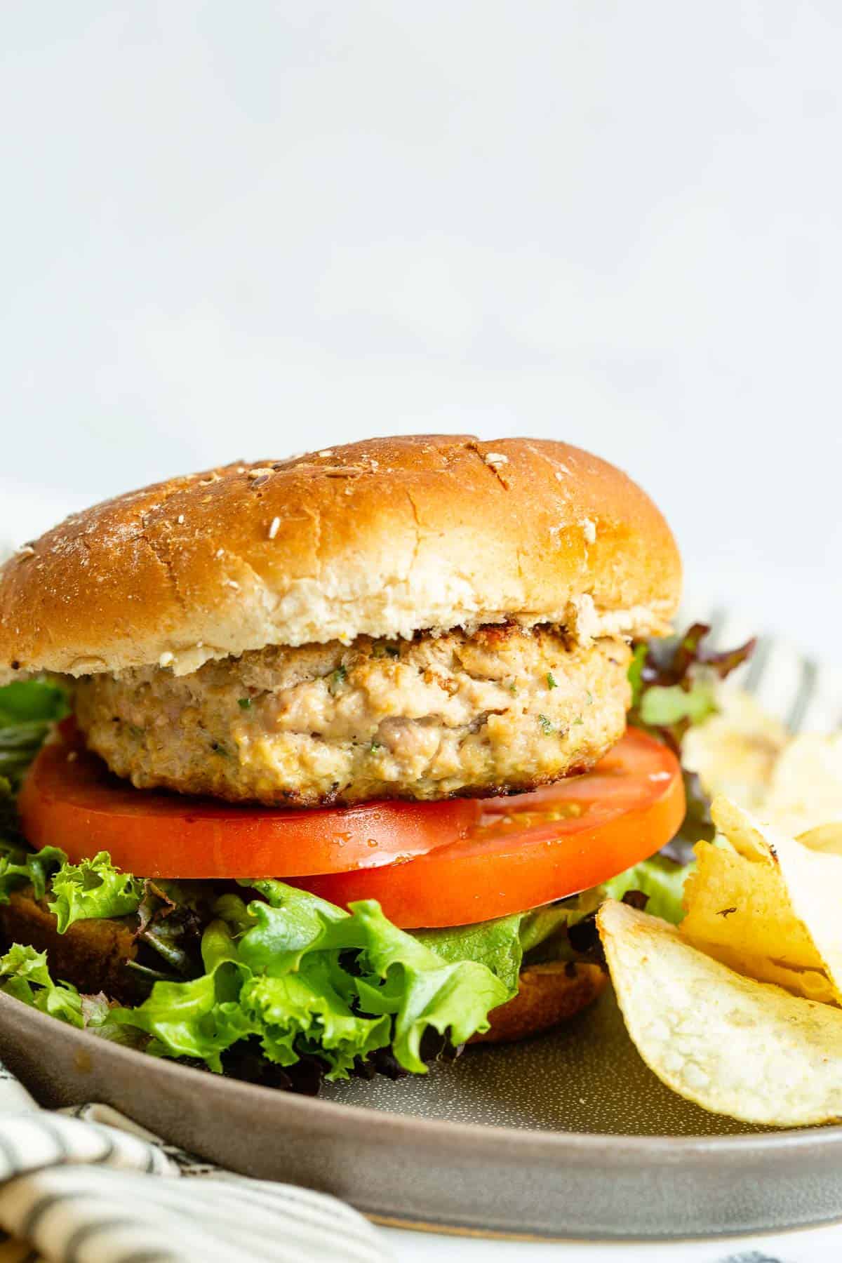 Close up of a turkey burger on a bun with lettuce and tomato.