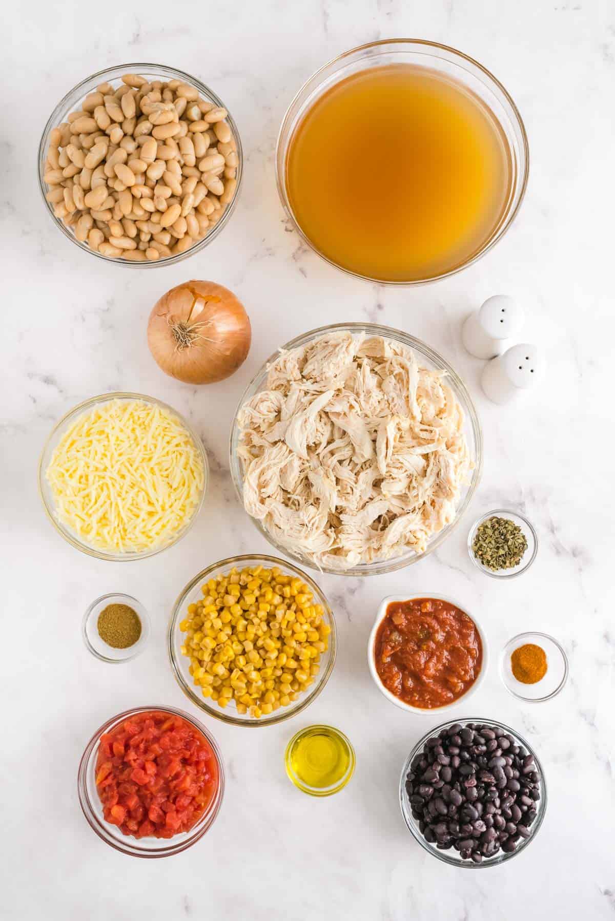 Overhead view of ingredients needed for white chili, all in glass bowls.