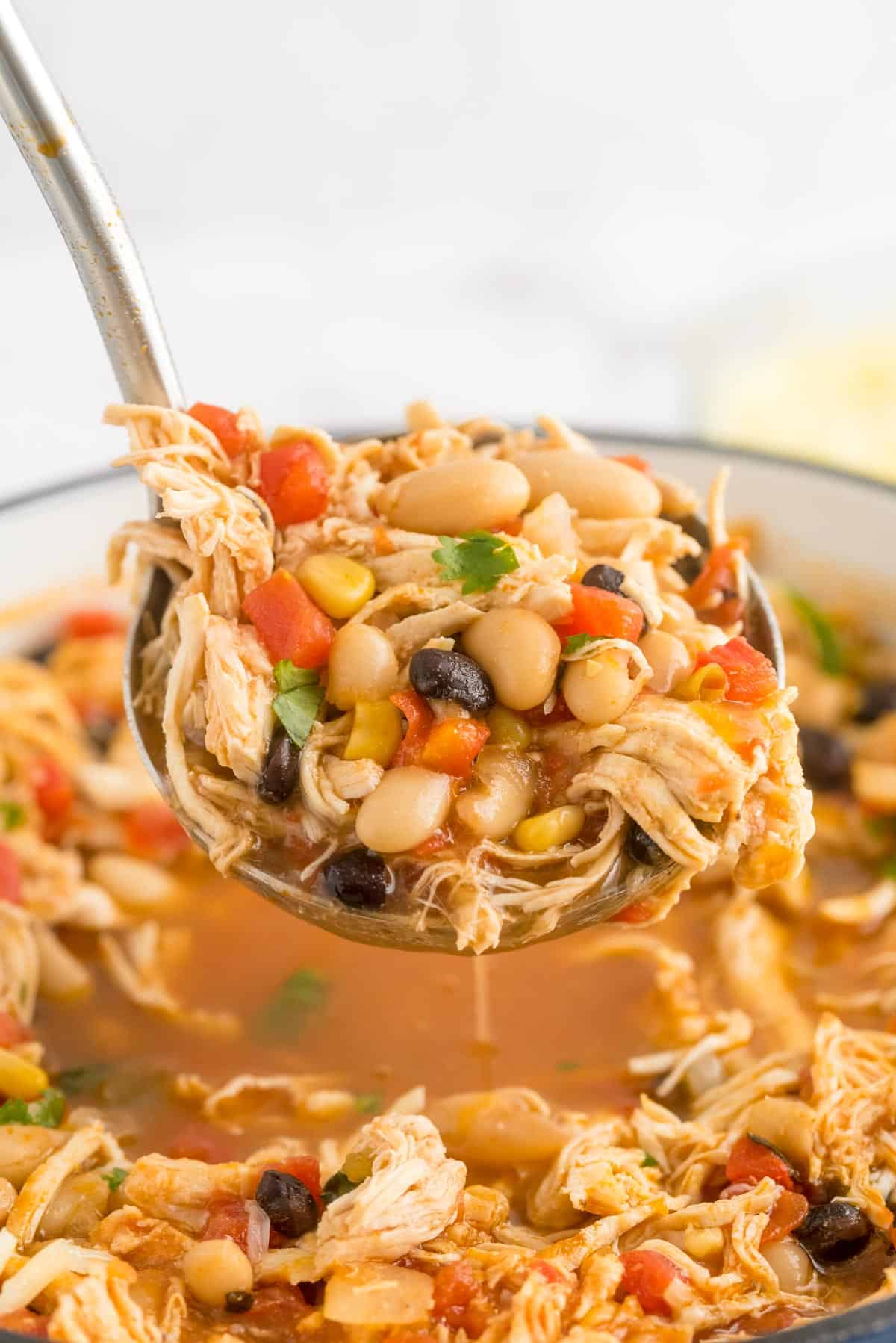 White chicken chili being ladled out of a pot.