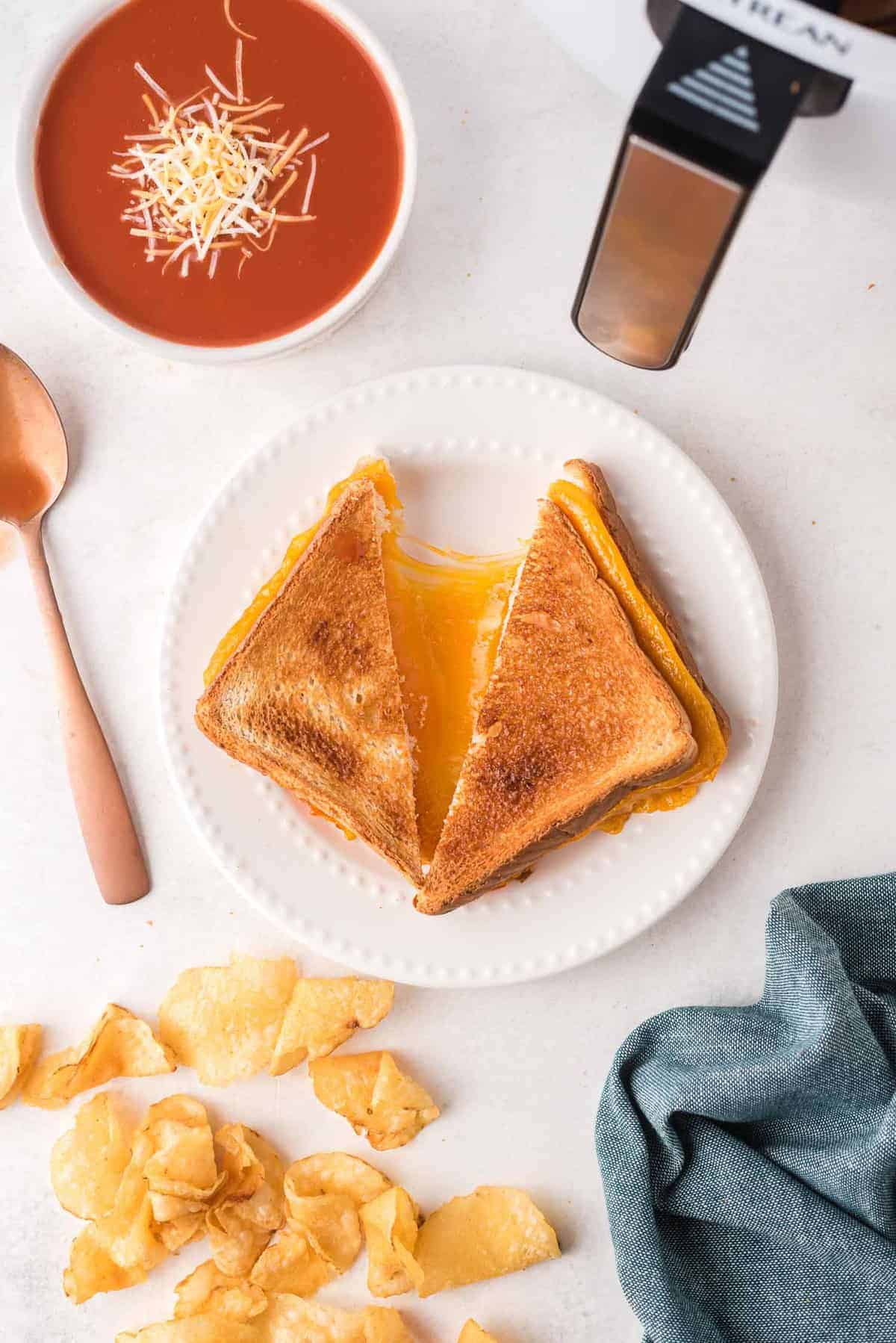 Overhead view of a grilled cheese sandwich on a white plate, being pulled apart to show cheese.