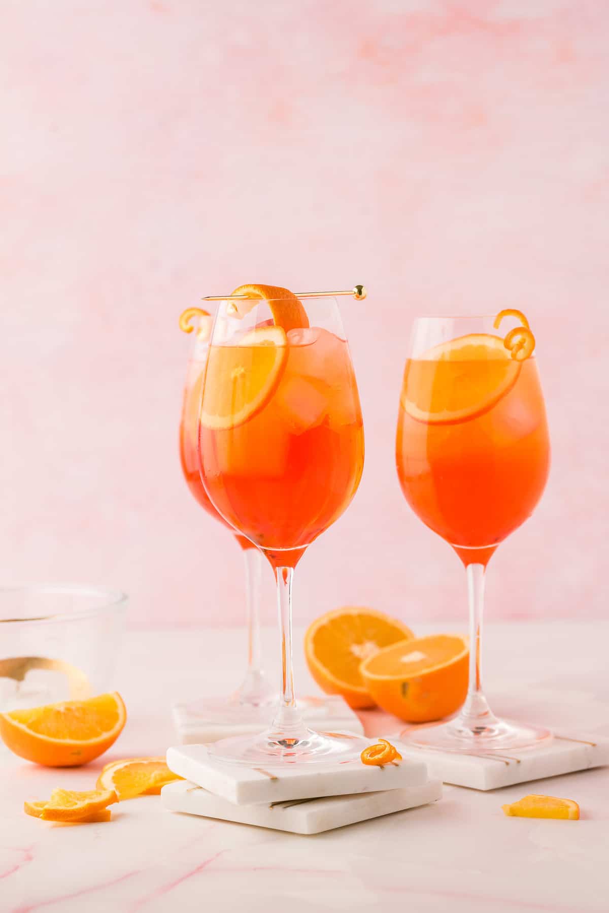 Three wine glasses filled with an orange drink and orange slices.