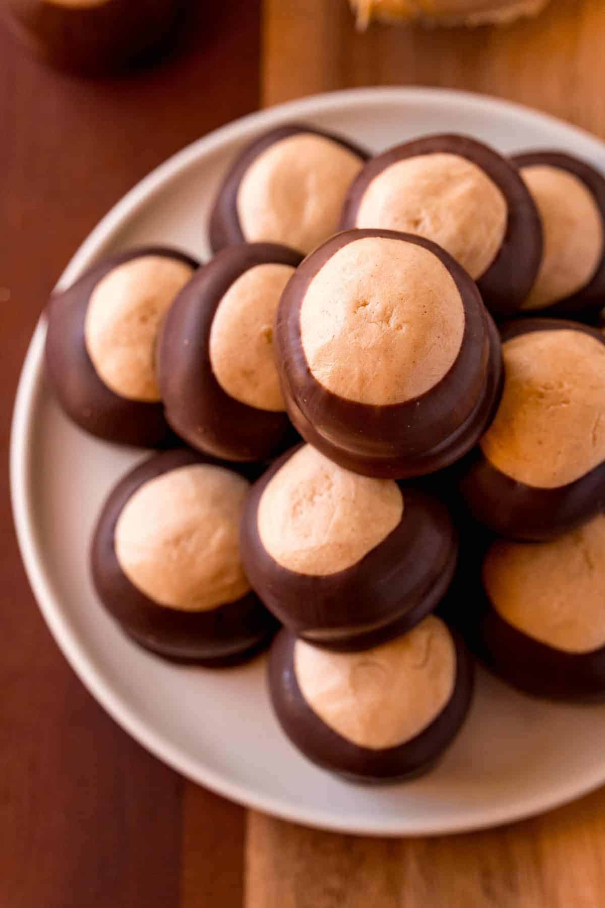 A pile of buckeyes candy on a plate on a wooden background.