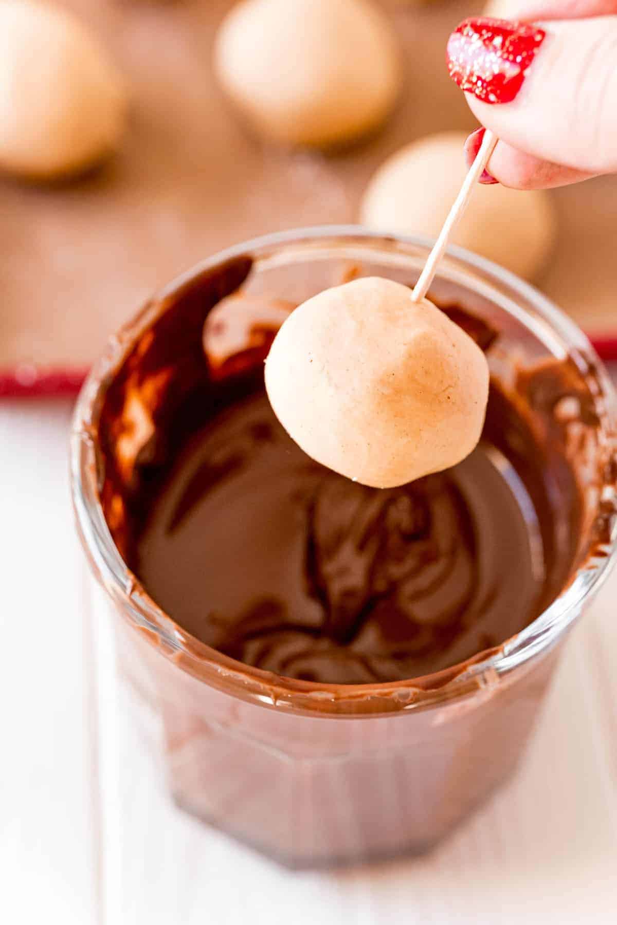 Peanut butter ball being dipped in chocolate.