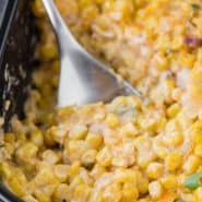 Creamy cheesy corn in a black casserole dish with a text overlay containing the recipe title.