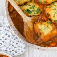 Overhead view of chicken with dumplings, text overlay reads "one pan chicken with cornmeal dumplings"