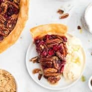 Pie slice on a white plate, text overlay reads "pecan cranberry pie, rachelcooks.com"