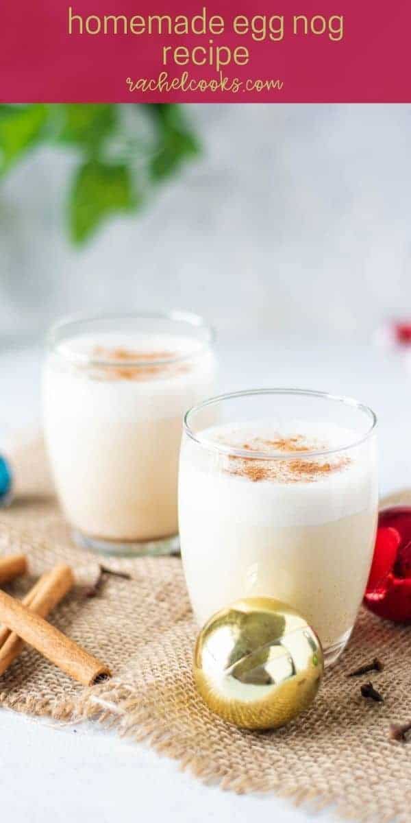 Two glasses of egg nog surrounded by Christmas ornaments.