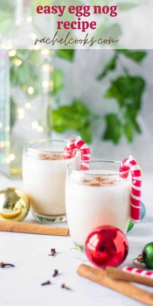 Two glasses of egg nog surrounded by Christmas ornaments.