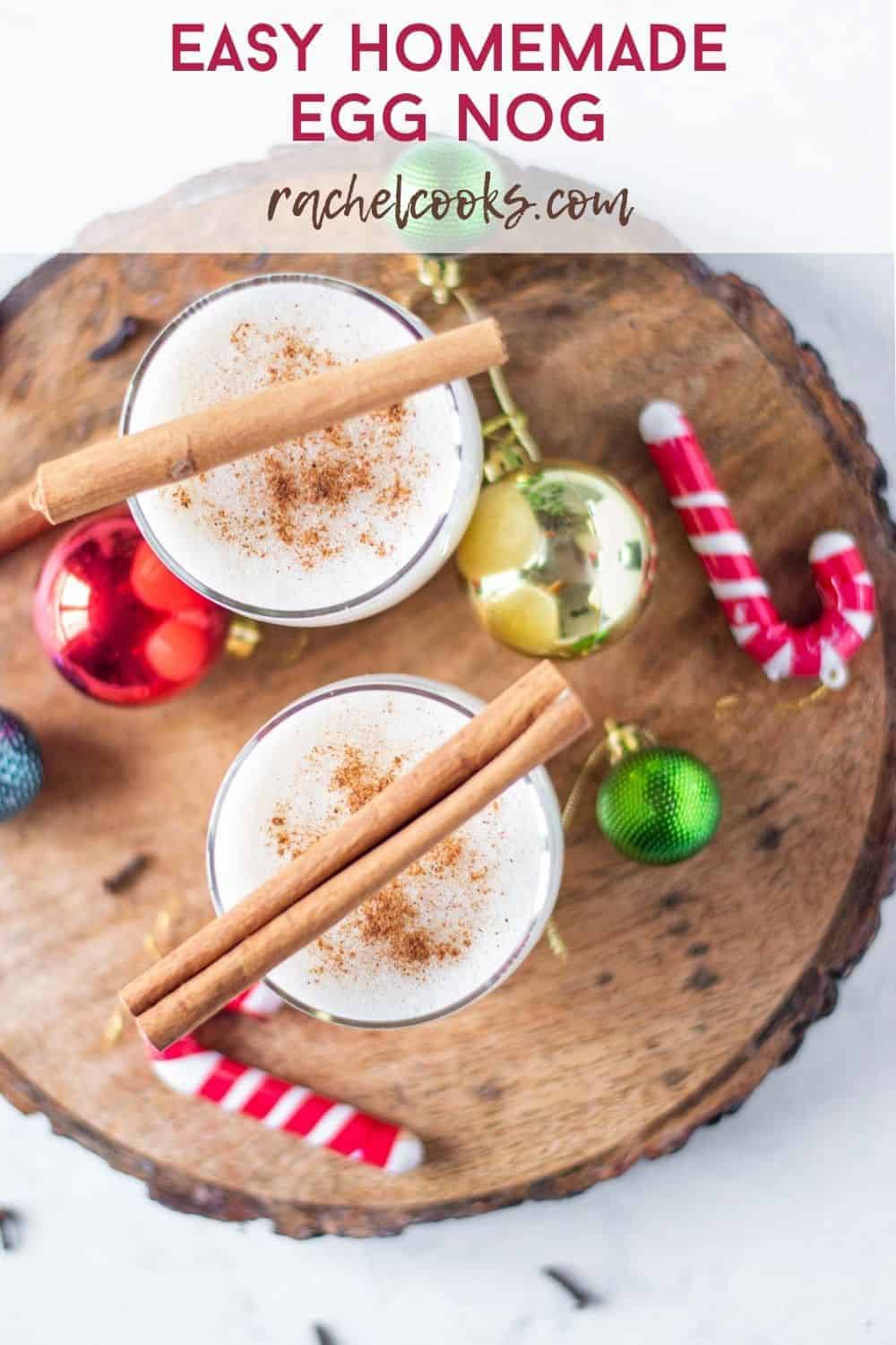 Overhead view of two glasses of egg nog, topped with cinnamon sticks.