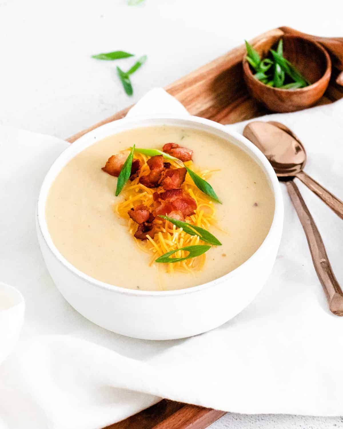 Soup in a bowl on a tray with spoons.