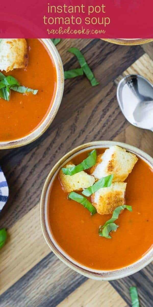 Overhead view of two bowls of tomato soup topped with croutons and fresh basil.