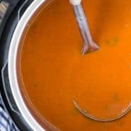 Tomato soup in an instant pot with a ladle.