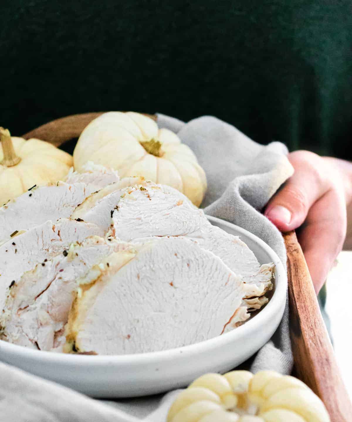 Slices of turkey on a platter being carried by a person in a dark green shirt.